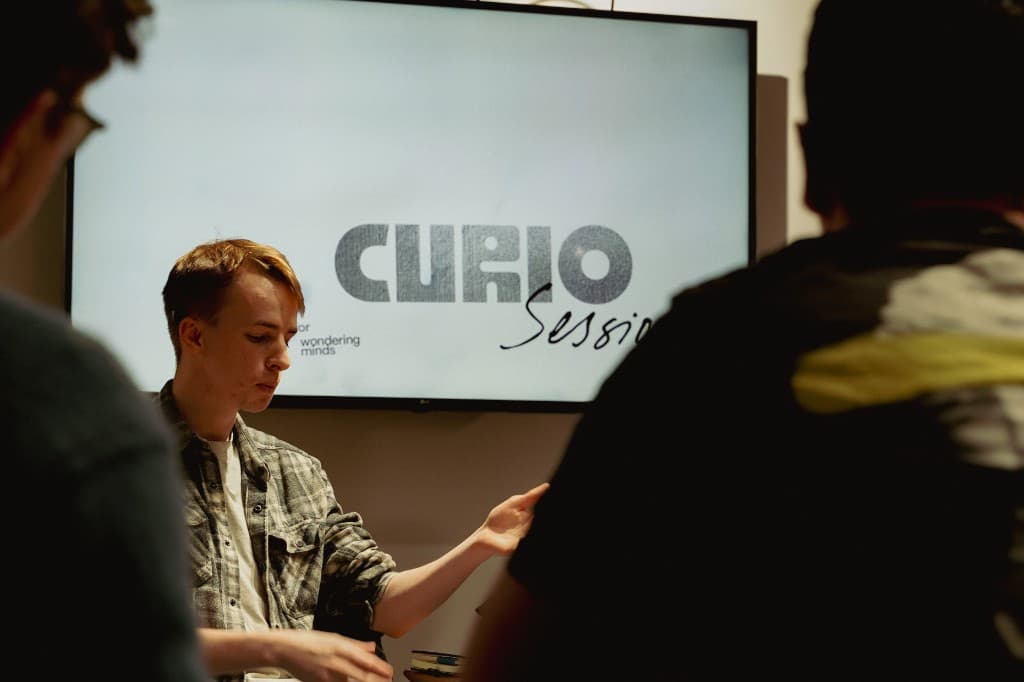 Paul speaking at Curio Sessions, with the event title on the screen behind him.