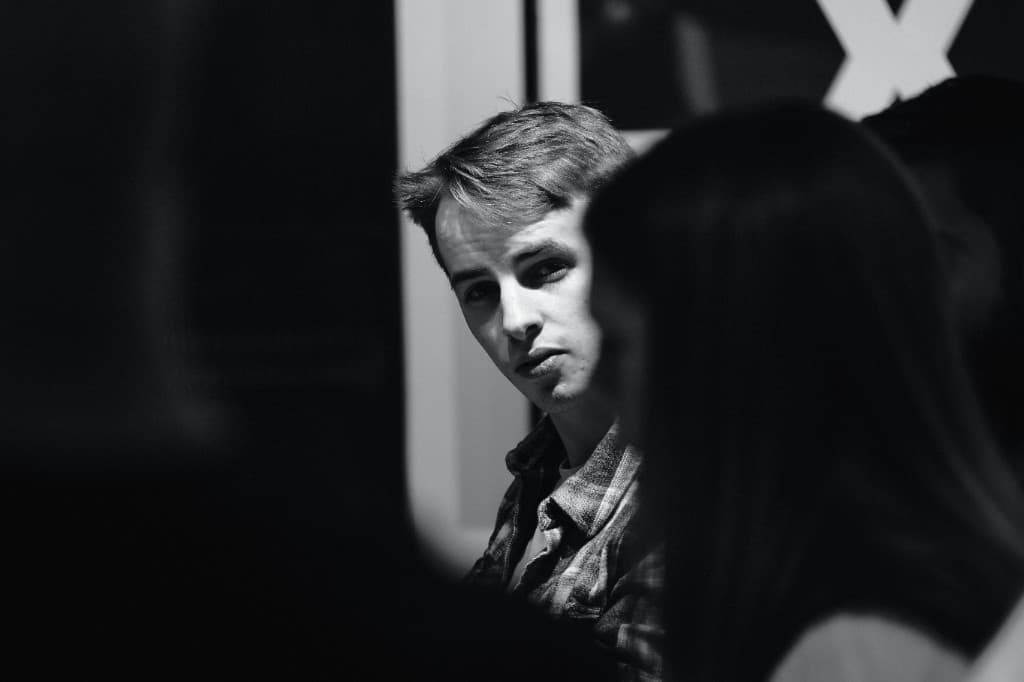Paul Wilson in a room of people, photographed in black and white.